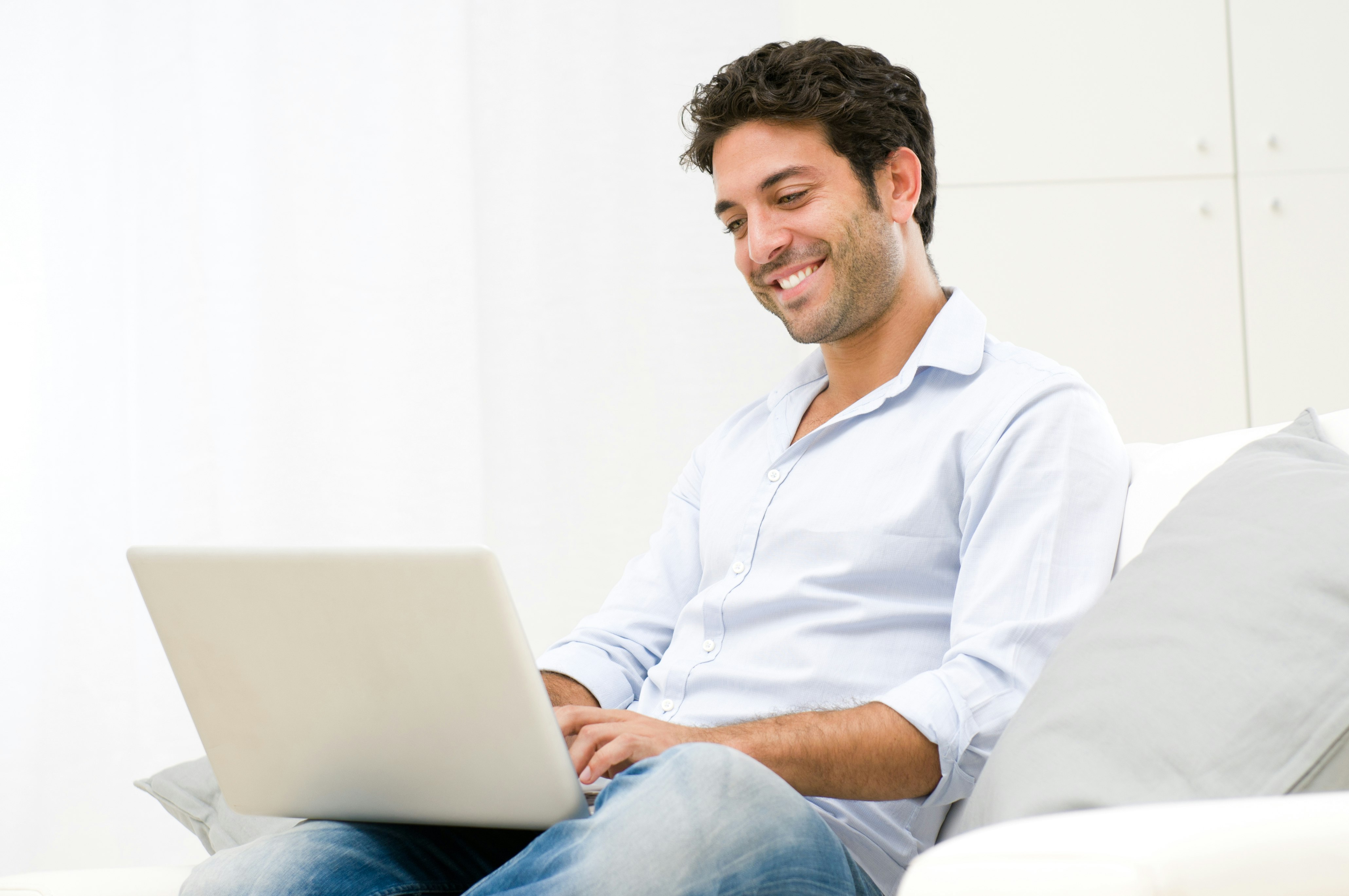 Happy smiling young man watching and working on computer laptop at home
