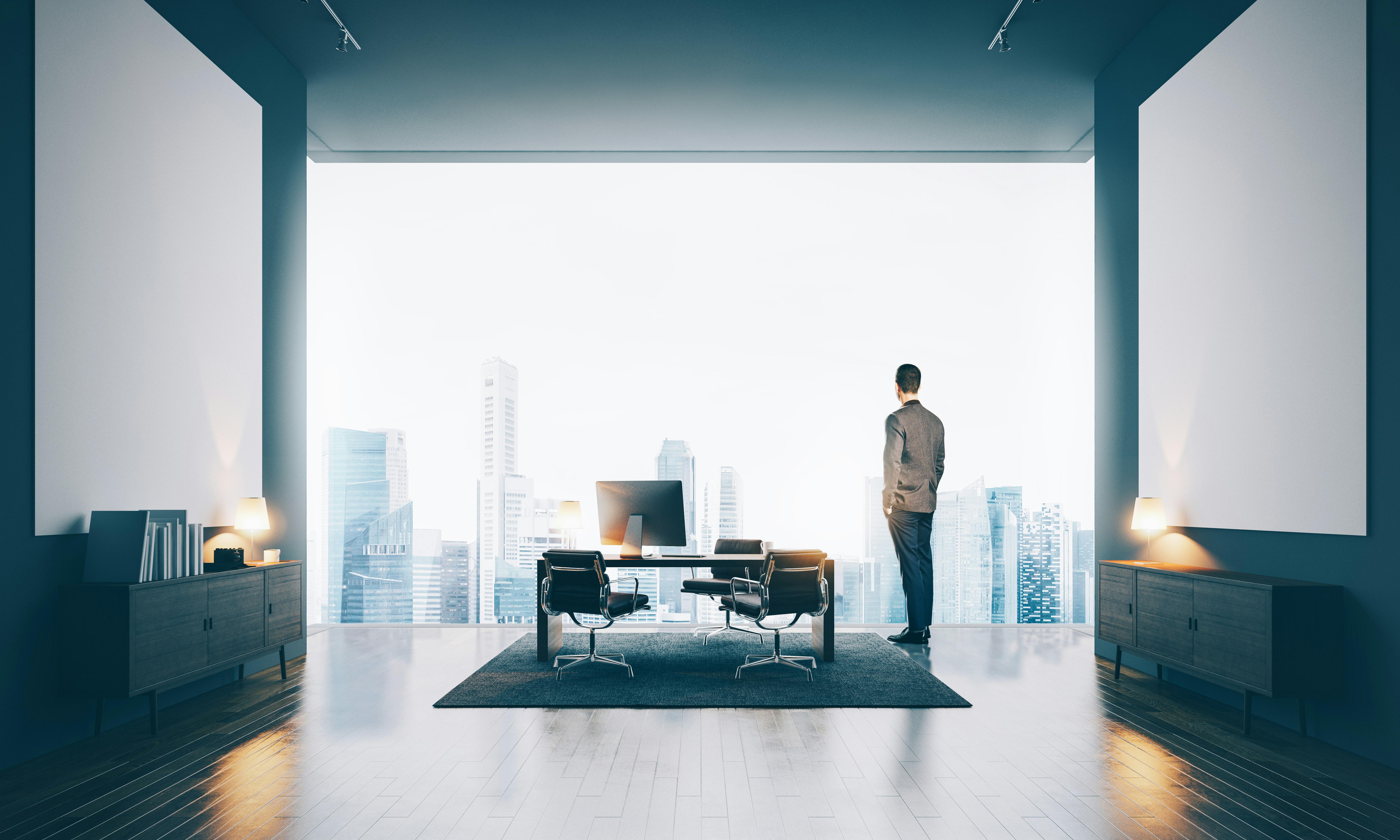 Businessman wearing modern suit and looking at the city in contemporary office. Workspace in loft with white canvas